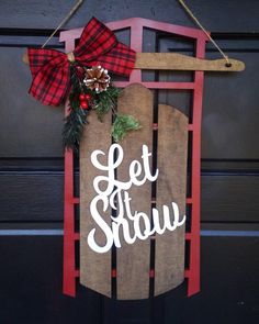 a wooden sled with the words let it snow hanging on a door hanger