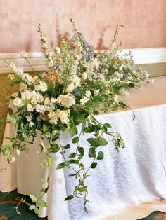 a vase filled with flowers sitting on top of a table next to a white table cloth