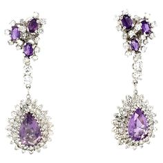 This exquisite pair of mid-century dangle earrings in 14K white gold features a captivating combination of amethysts and diamonds, embodying the elegance of the 1950s. The earrings showcase a total of 8 pear and oval-cut amethysts, weighing approximately 5 carats, each with a rich, deep purple hue that brings vintage charm to the design. Surrounding and enhancing the amethysts are 114 round brilliant-cut diamonds, totaling 2.65 carats, with K-L color and SI-2 clarity, adding a sparkling contrast Diamond Dangle Earrings, Fashion Pieces, Purple Hues, Amethyst Stone, Round Brilliant Cut Diamond, Deep Purple, Vintage Charms, Round Brilliant, Beautiful Jewelry