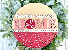 a wooden sign that says home sweet home surrounded by greenery on a white background