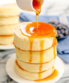 a stack of pancakes with syrup being drizzled on top