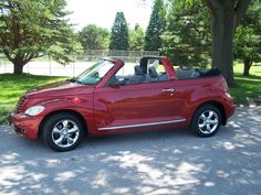 a small red convertible car parked in a driveway