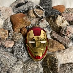 the iron man mask keychain is laying on some rocks