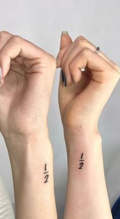 two people with matching tattoos on their arms, one is holding the other's hand