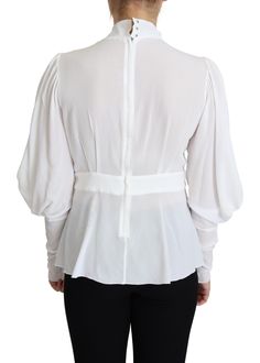 Exude sophistication with this pristine Dolce & Gabbana snow-white blouse, perfect for elevating your wardrobe. Crafted in Italy, this stunning piece showcases an ascot collar and long lantern sleeves. The fitted silhouette is rendered in a sumptuous blend of viscose and elastane, ensuring a comfortable and flattering fit. The front features a polished placket with fabric-covered buttons, adding a touch of elegance. Material: 95% Viscose 5% Elastane Color: White Country of origin: Italy Logo det Viscose Blouse, White Silk Blouse, Lantern Sleeve Top, Collared Top, Gorgeous Blouses, Fabric Covered Button, Dolce E Gabbana, Collar Top, Fitted Silhouette