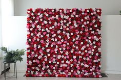 a large red and pink flowered wall hanging on the side of a white wall