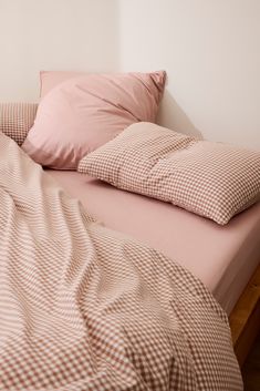 an unmade bed with two pillows on top of it and a pink comforter