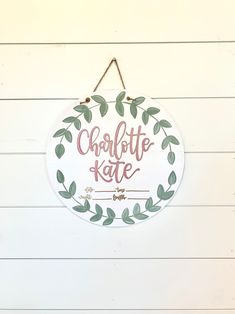 a sign hanging on the side of a building that says charlotte kate with leaves around it