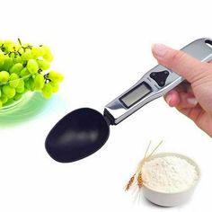 a hand holding a spoon with grapes in it and a measuring scale next to it