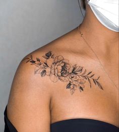 a woman wearing a face mask with flowers on her shoulder and chest tattoo design in black ink