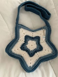 a blue and white crocheted bag sitting on top of a bed next to a pillow