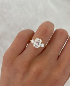 a woman's hand with a three stone ring on it