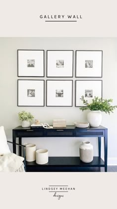 a black table with white vases and pictures on the wall above it in a living room