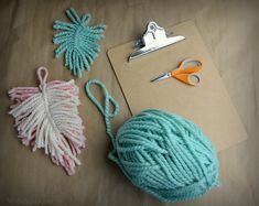 yarn and scissors are on the table next to a clipboard