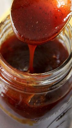 a spoon full of bbq sauce on top of a jar