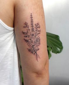 a woman with a tattoo on her arm has a bouquet of wildflowers in it