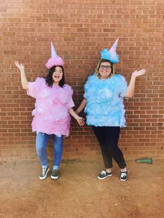 two women dressed in costumes standing next to a brick wall