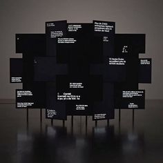 an art installation consisting of black squares with white text on the sides and dark background