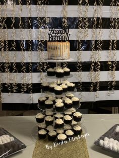 a cake and cupcakes on a table in front of a black and white striped backdrop