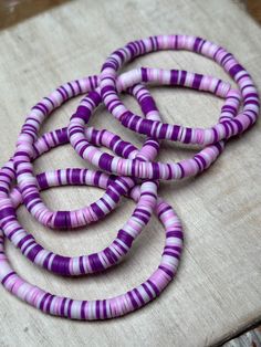 purple and white beads are arranged on a piece of wood