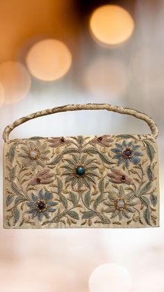 This stunning 1950s gold satin clutch/bag has been intricately hand embroidered in the zardozi style with shimmery gold metallic threads, embellished with genuine semi-precious stones, creating an opulent and sophisticated effect.  The front of this clutch features the amazing hand embroidered design, and the back is solid satin with an attached hand strap with embroidered detail. There is an attached gold satin cord crossbody strap which can easily be tucked inside if you like. The interior is Festive Rectangular Clutch With Gold Embroidery, Rectangular Gold Embroidered Evening Bag, Festive Rectangular Evening Bag With Gold Embroidery, Festive Gold Embroidered Rectangular Evening Bag, Traditional Rectangular Evening Bag With Gold Embroidery, Traditional Gold Clutch With Gold Embroidery, Gold Evening Bag With Handwork For Reception, Gold Shoulder Bag With Zari Work For Evening, Evening Gold Shoulder Bag With Zari Work