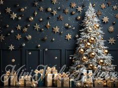 a christmas tree with gold and silver presents in front of a wall decorated with stars