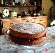 a cake sitting on top of a glass plate covered in powdered sugar and jelly