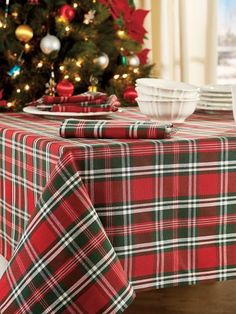 a plaid table cloth is on top of a dining room table next to a christmas tree