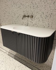 a white sink sitting next to a wall mounted faucet