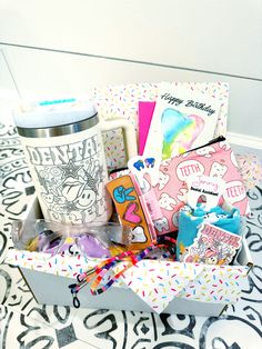 a box filled with lots of different items on top of a floor covered in confetti