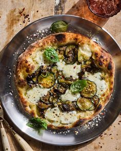 a pizza sitting on top of a metal pan covered in cheese and veggies