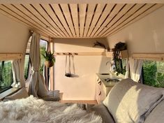 the interior of a tiny home with white fur on the bed and windows in it