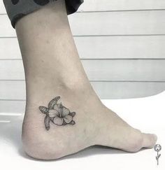 a small turtle and flower tattoo on the ankle