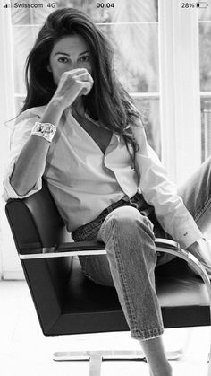 a black and white photo of a woman sitting in a chair with her legs crossed