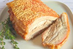 a piece of meat on a white plate with some parsley next to it and a sprig of thyle