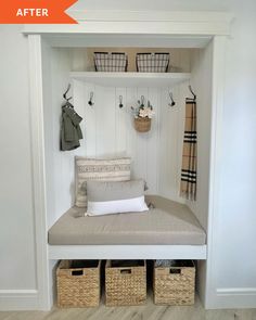 a white bench with baskets and coat hooks on the wall next to an entryway