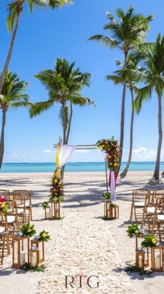 an outdoor ceremony set up on the beach with palm trees and white linen draped chairs