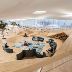 people are sitting on couches in an open area with stairs and bookshelves