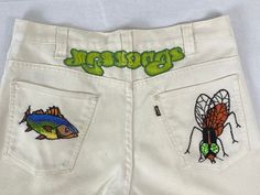 "Vintage 1970s Levi's Sta Prest pants. Made of cotton/poly white denim. Has Rock and Roll band, fly and fish embroidered on back. Intricate embroidery! \"YES SONGS\" Has Levis big E label, Talon zip fly, two waist pockets, and two rear pockets. Label reads: Levis sta-prest never needs ironing. Style 546. Actual measurements are:  32\" at the waist  33\" inseam  43\" hips  24\" thighs  11\" rise  Overall length 44\"  20\" foot opening In good condition. Some faint yellow areas throughout." Retro White Bottoms For Streetwear, Vintage White Streetwear Bottoms, Vintage White Bottoms For Streetwear, Vintage Style White Bottoms For Streetwear, White Retro Pants For Streetwear, White 90s Style Cotton Pants, White Cotton 90s Style Pants, White Embroidered Cotton Jeans, Retro White Bottoms With Pockets