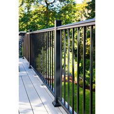 a black metal fence on the side of a wooden deck with trees in the background