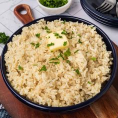 rice with butter and parsley in a blue bowl on a wooden cutting board next to other dishes