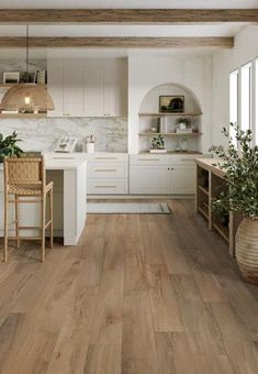 an open kitchen with white cabinets and wood flooring, along with potted plants on the counter