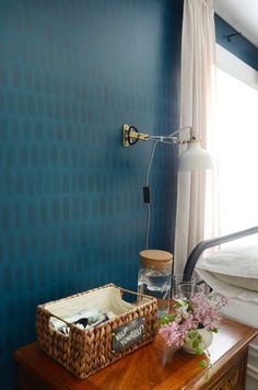 a bedroom with blue walls and white curtains on the windowsill is decorated with wicker baskets