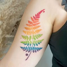 a woman's arm with a colorful fern tattoo on the left side of her arm