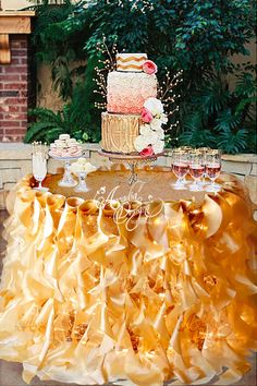 a table topped with a cake covered in yellow ruffles and glasses filled with wine