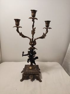 an ornate bronze candelabra with five candles on it's base, in front of a white background