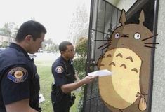 two police officers standing in front of a door with an image of a cat on it