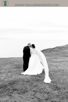 a bride and groom standing on top of a grass covered field next to the ocean