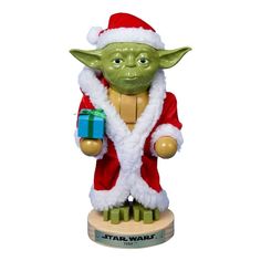 a star wars figurine is holding a gift box and wearing a santa claus outfit