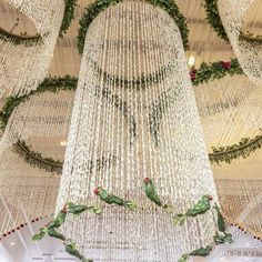 the chandelier is hanging from the ceiling and decorated with white beads, greenery and red berries